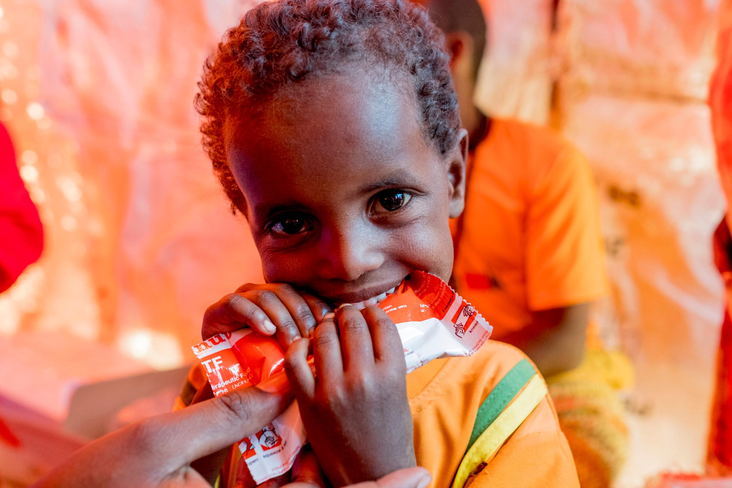 A young child eats a packet of ready-to-use therapeutic food at a World Concern nutrition site.